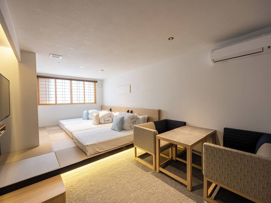 A modern hotel room with a bed, a desk, a chair, a TV, and a window.