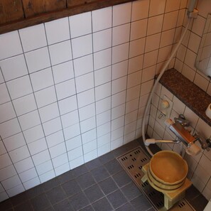 A bathroom with white tiled walls, a brown countertop, and a shower area. - Yamadaya Hotel (Fujikawaguchiko)