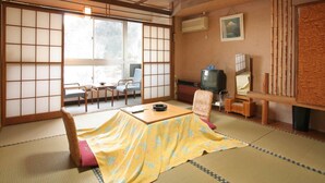 A traditional Japanese room with tatami flooring, a low table, and a television.