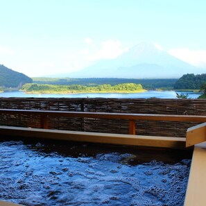 Une vue sur une montagne, prise depuis une terrasse en bois, avec un plan d’eau au premier plan.