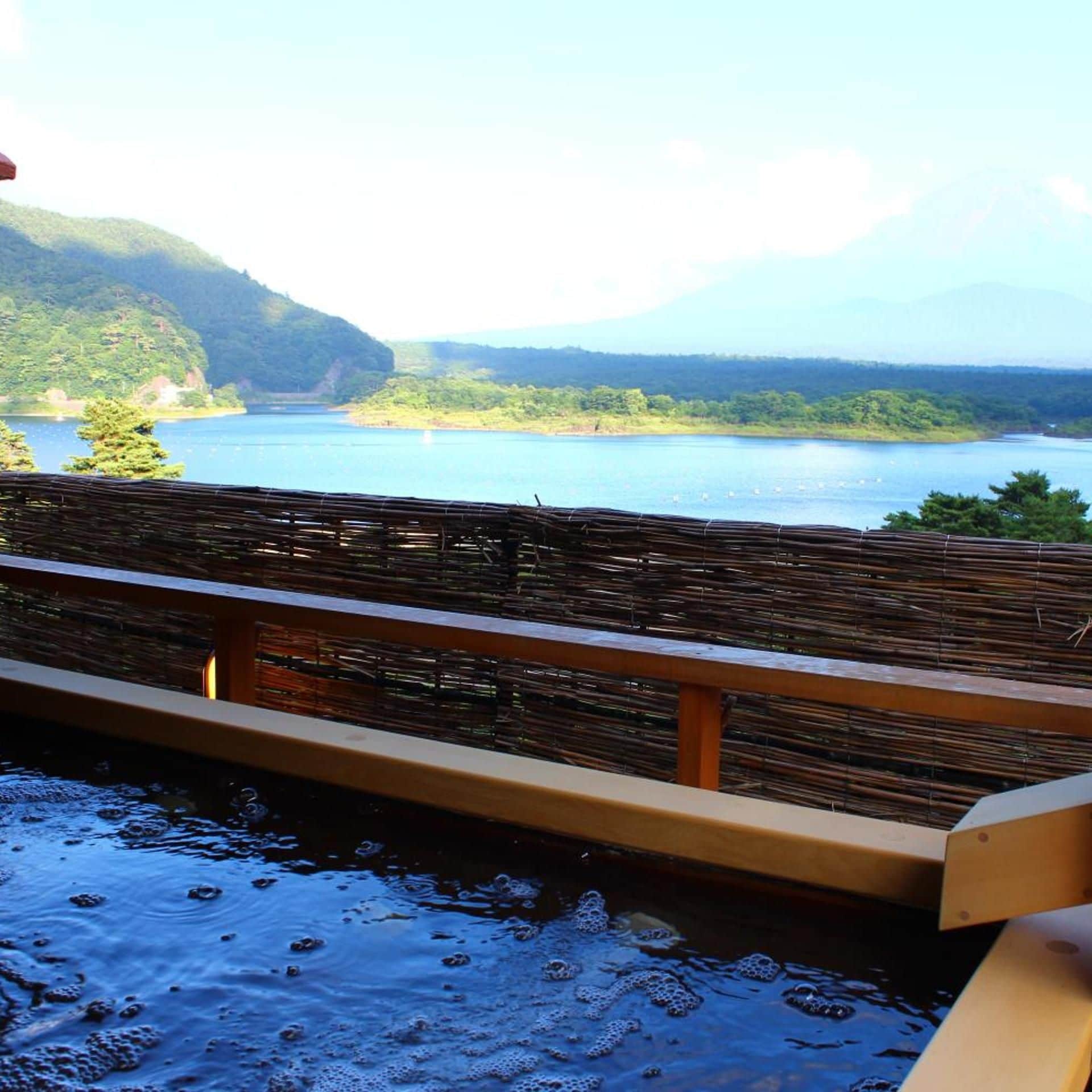 A wooden deck overlooking a calm lake with mountains in the background.