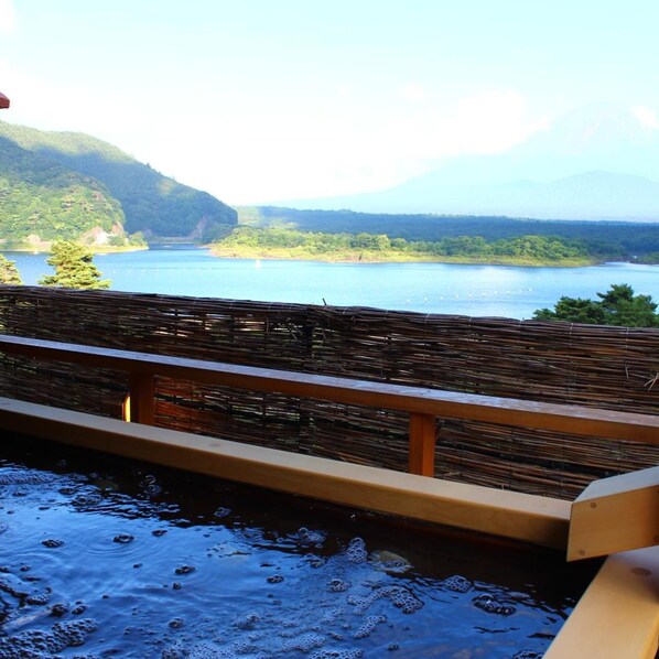 A wooden deck overlooking a calm lake with mountains in the background.
