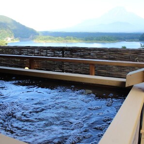Un élément décoratif aquatique agrémenté d’une balustrade en bois, avec vue sur un lac et des montagnes en arrière-plan.