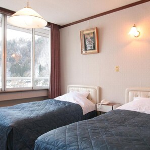 Une chambre d’hôtel avec deux lits, une fenêtre avec des rideaux, un tableau accroché au mur et une lampe de chevet.