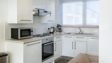 Una cocina moderna con armarios blancos, microondas, horno y pileta.
