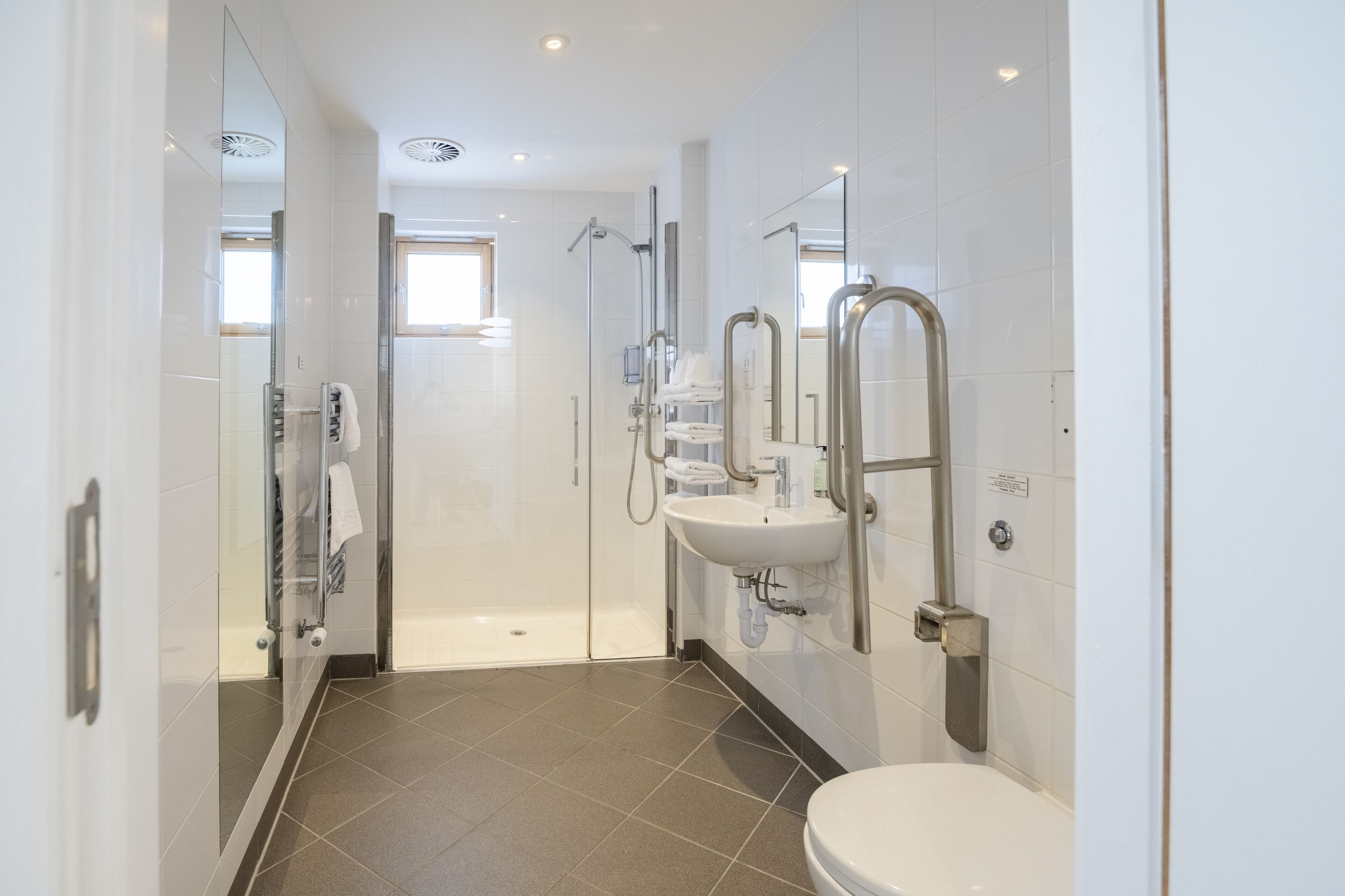 A modern bathroom with a glass-enclosed shower, a white sink, and a toilet.