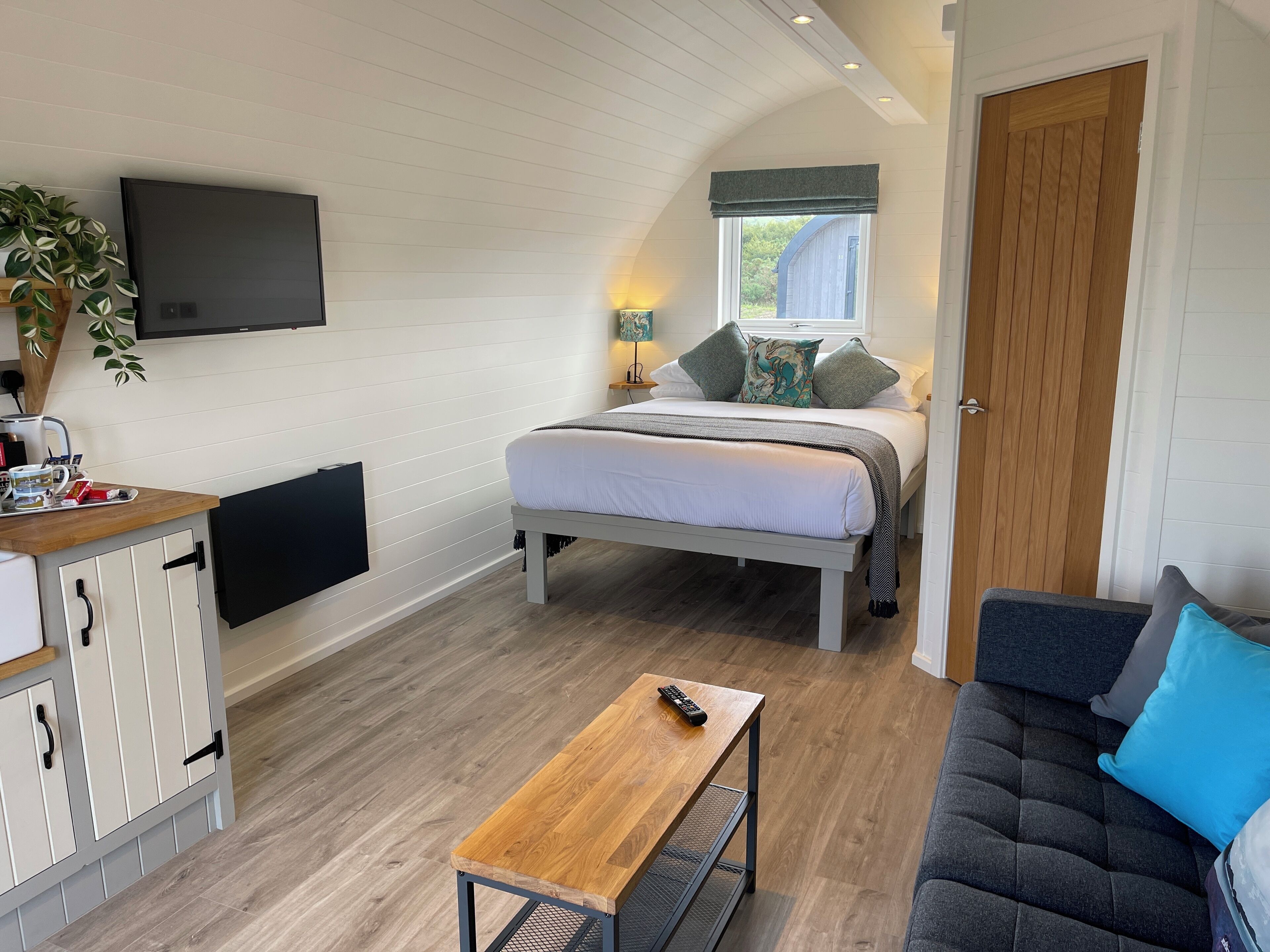 A bedroom with a bed, bedside table, and a TV mounted on the wall.