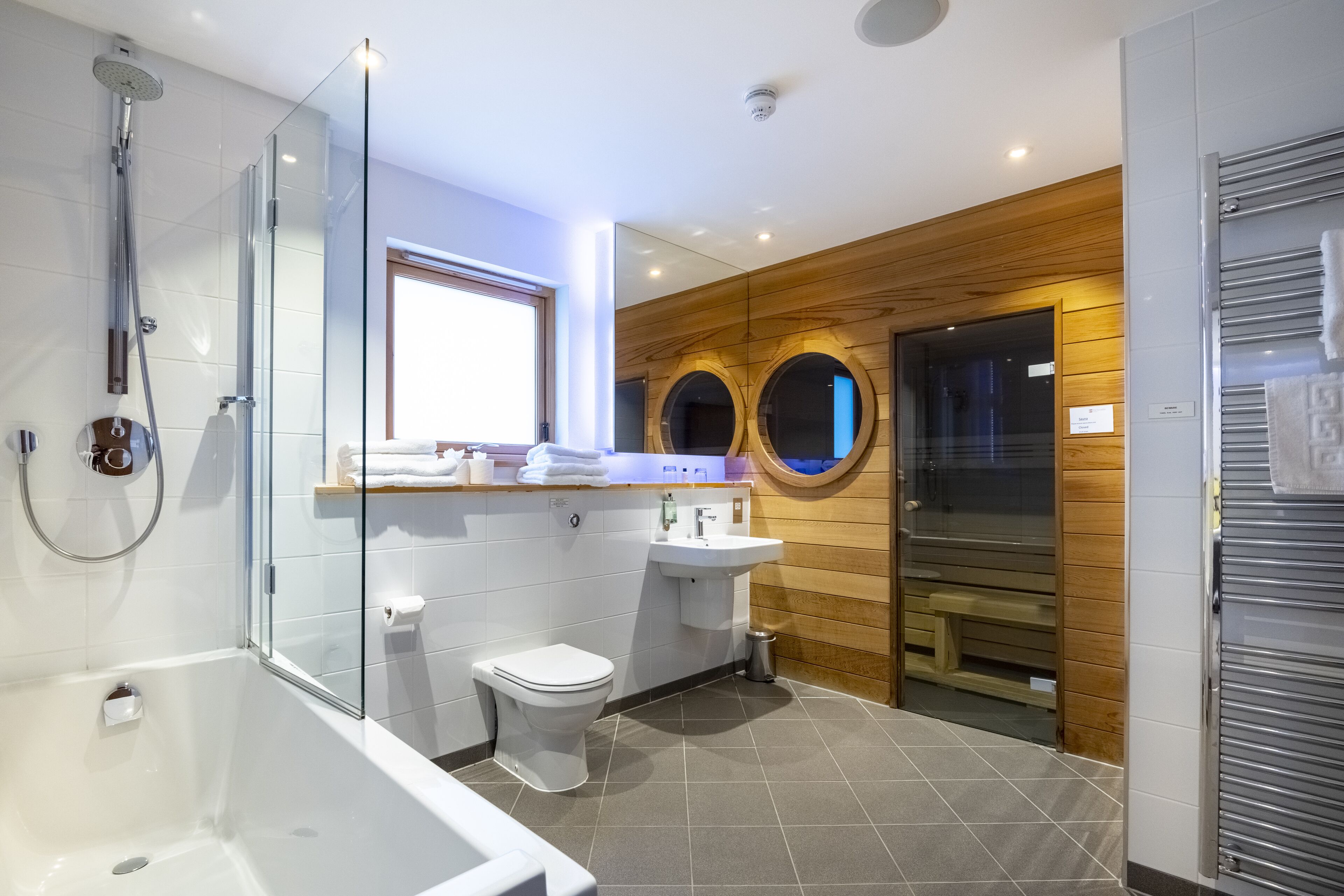 A modern bathroom with a glass-enclosed shower, a white toilet, and a wooden vanity with a sink.