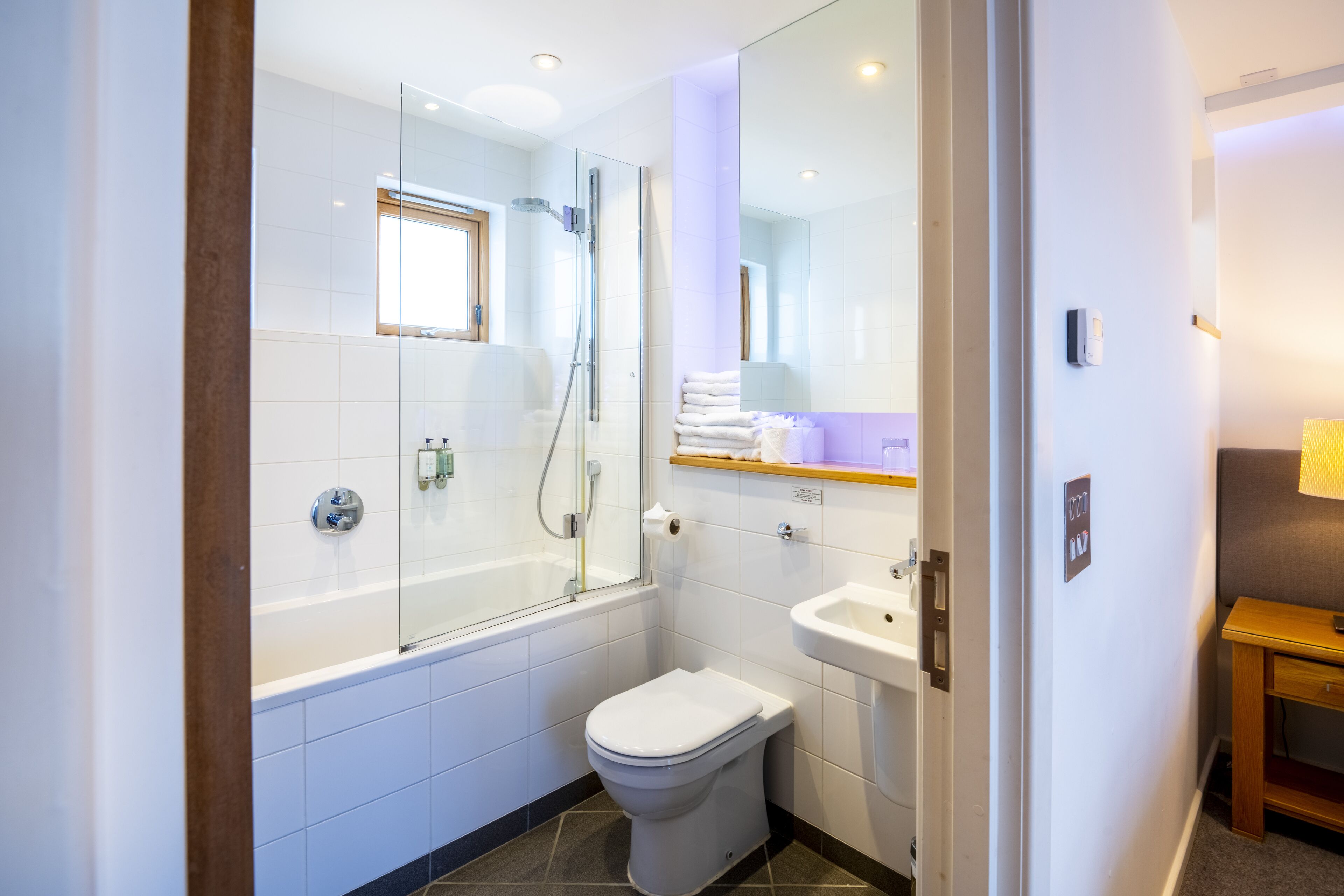 A modern bathroom with a glass-enclosed shower, a white toilet, and a sink.
