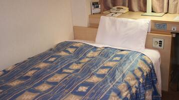 A hotel room with a bed, a desk, a telephone, and a nightstand.