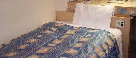 A hotel room with a bed, a desk, a telephone, and a nightstand.