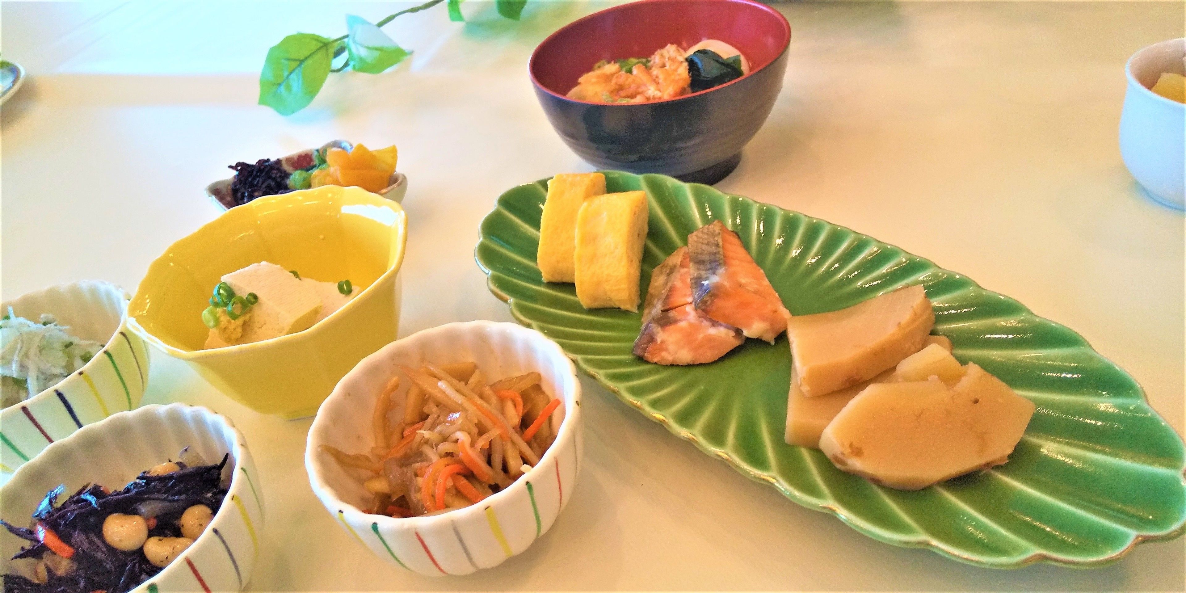 A table with various dishes including a salmon dish, a bowl of salad, and other food items.