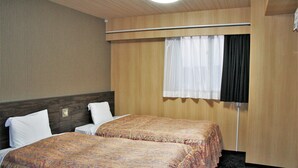 Una habitación de hotel con dos camas, una ventana con cortinas y un cabecero de madera.