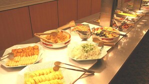 Una barra de buffet con diversos platos, incluyendo frituras, arroz y otros alimentos preparados.