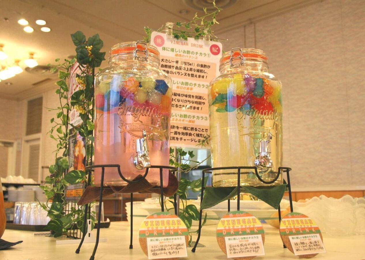 Una presentación de bebidas coloridas en frascos con etiquetas, y un cartelón al fondo.