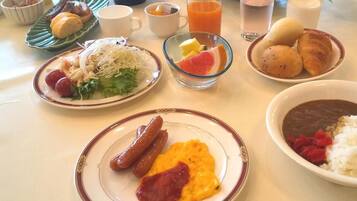 A breakfast table with various dishes including sausages, scrambled eggs, and a bowl of beans.