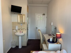 A hotel bathroom with a sink, mirror, and a television mounted above it. - Austins Self Service Guest House (Cardiff)