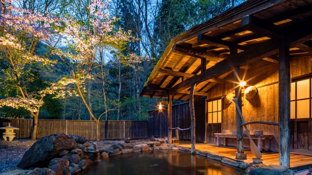 A wooden cabin with a stone pond, wooden deck, and a covered seating area. - Natsuse Onsen Miyakowasure (Senboku)
