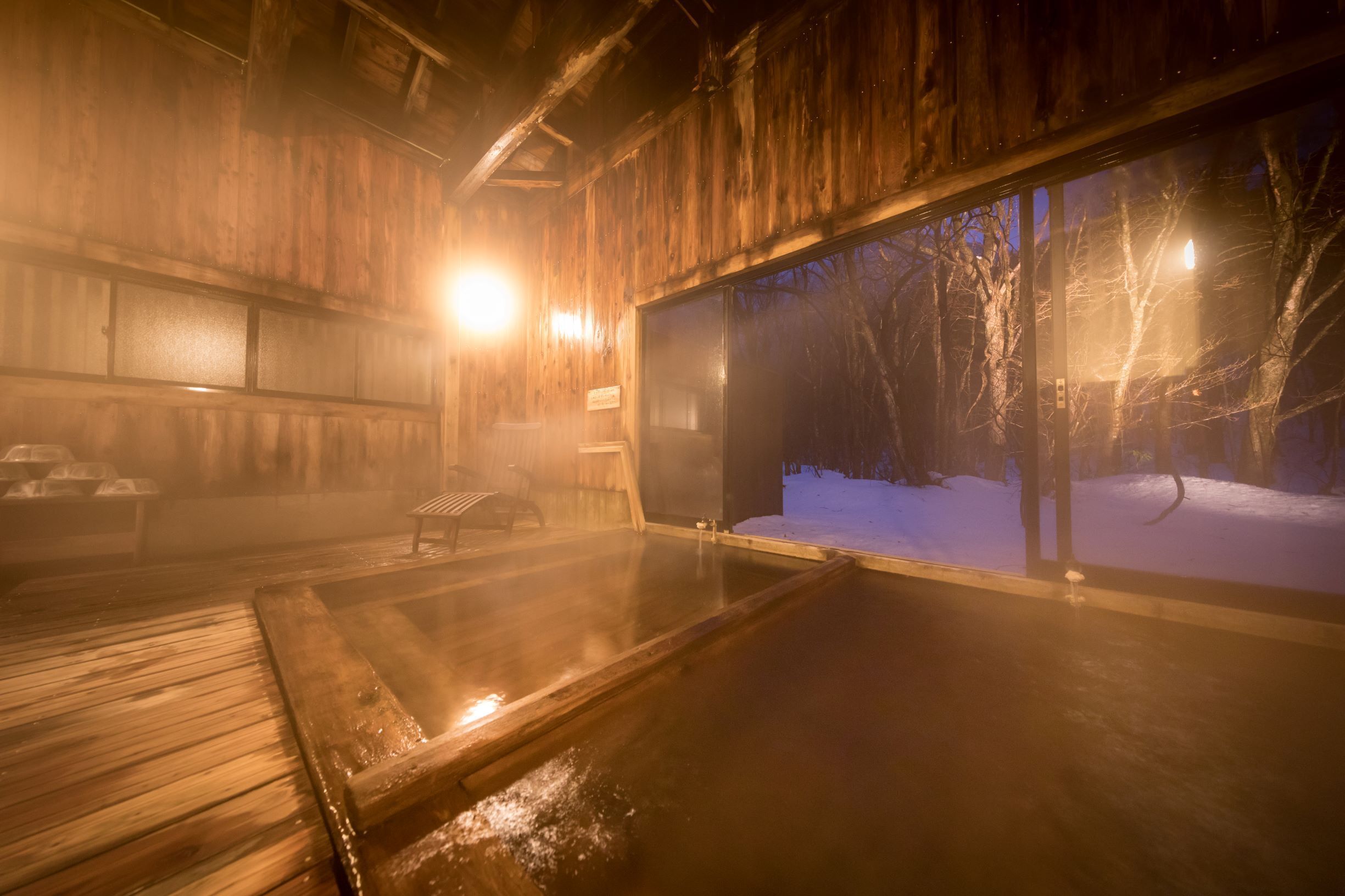 A wooden interior with a large glass window revealing a snowy outdoor scene.