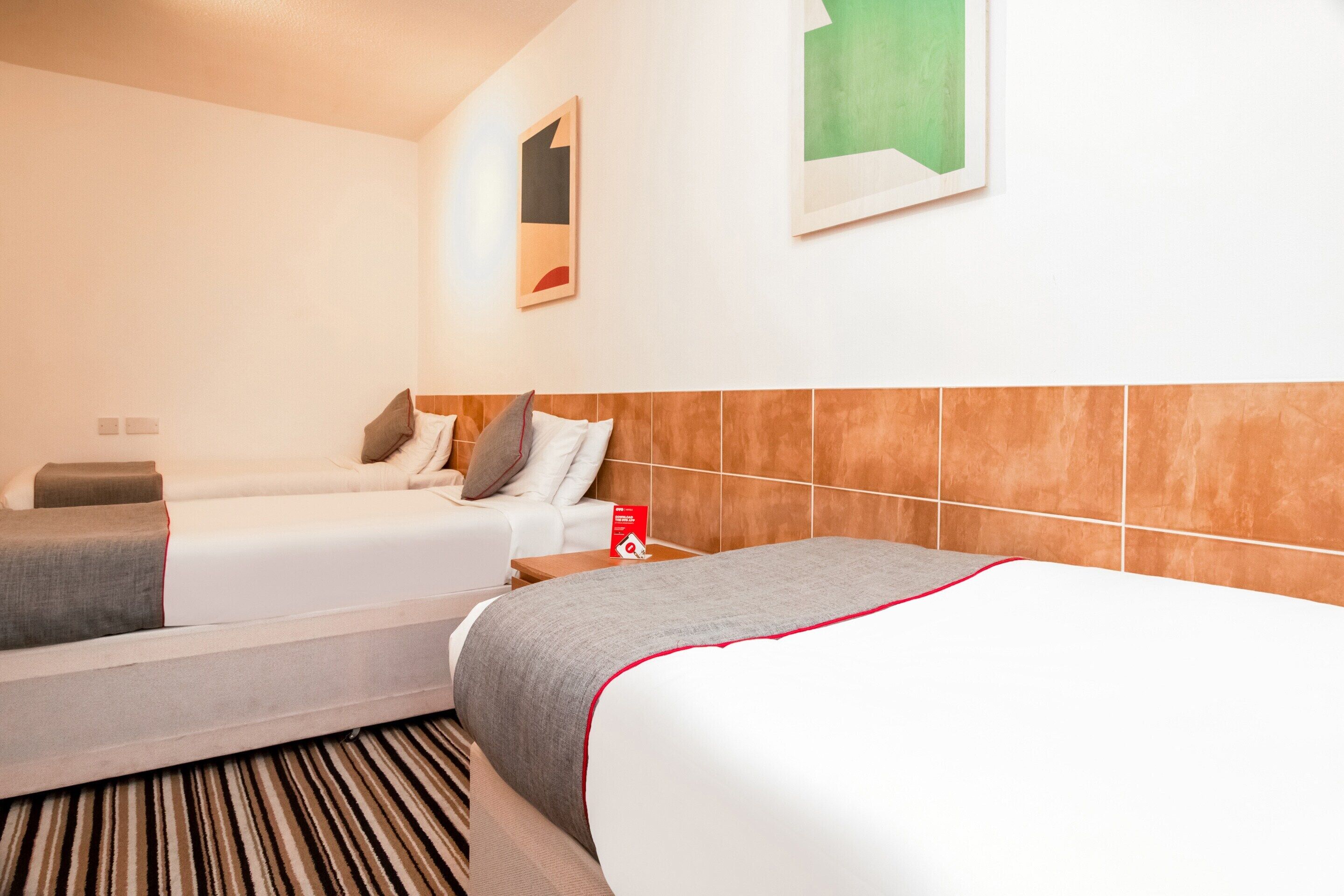Habitación de hotel con dos camas, alfombra a rayas y pared de azulejos.