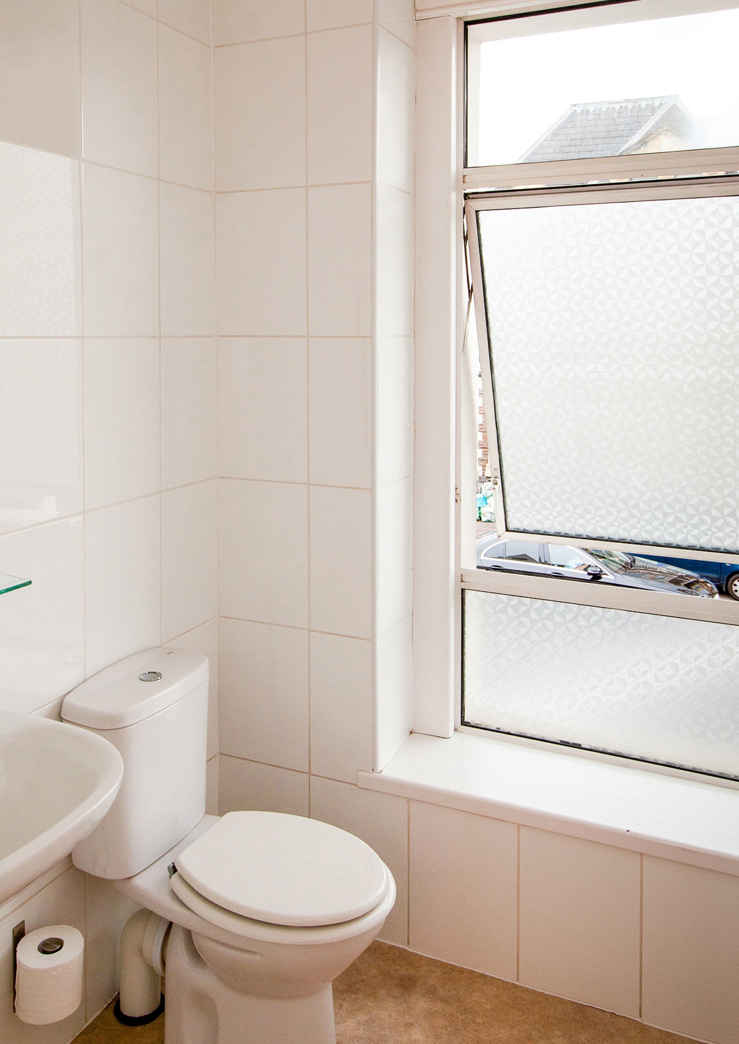 A bathroom with a toilet, sink, and window.