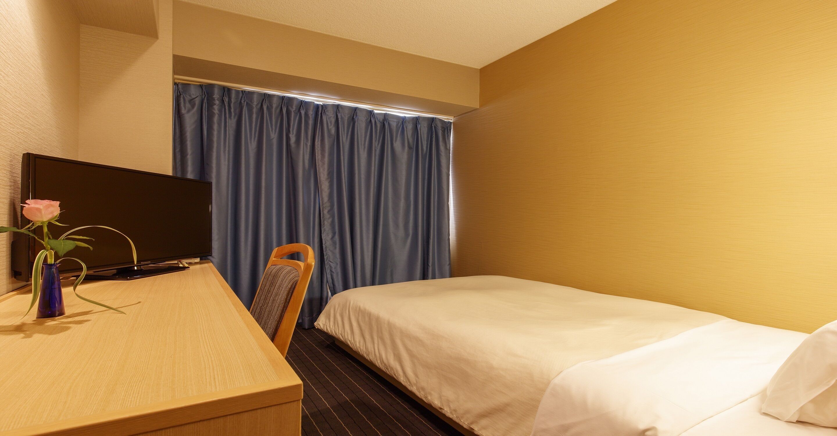 Une chambre d’hôtel avec un lit, un bureau équipé d’un ordinateur et une chaise.