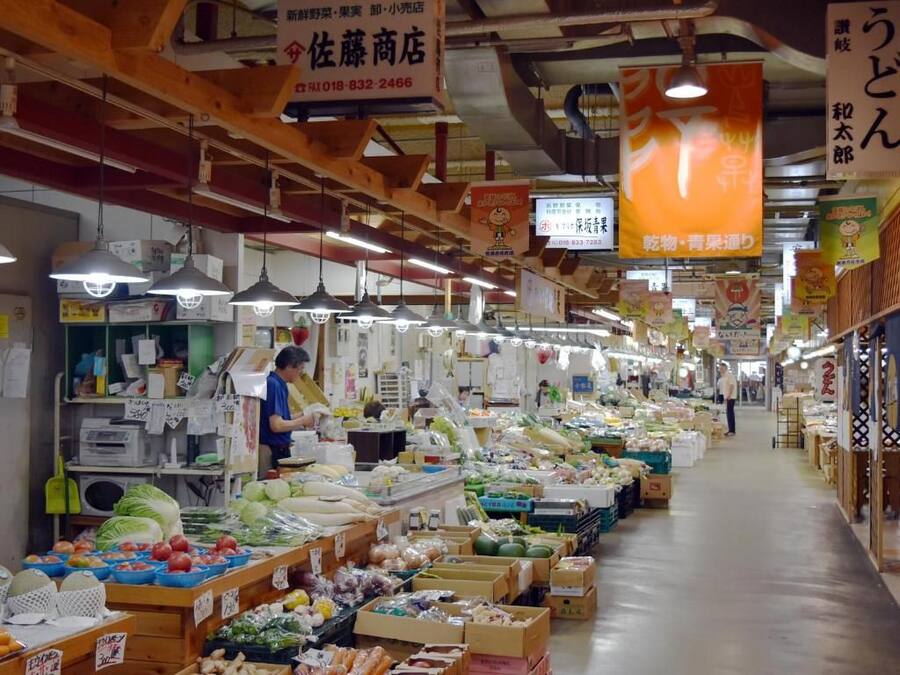 An indoor market with various stalls selling fresh produce and packaged goods.