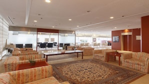 A spacious lobby with multiple seating areas, a large rug, and a modern ceiling design.