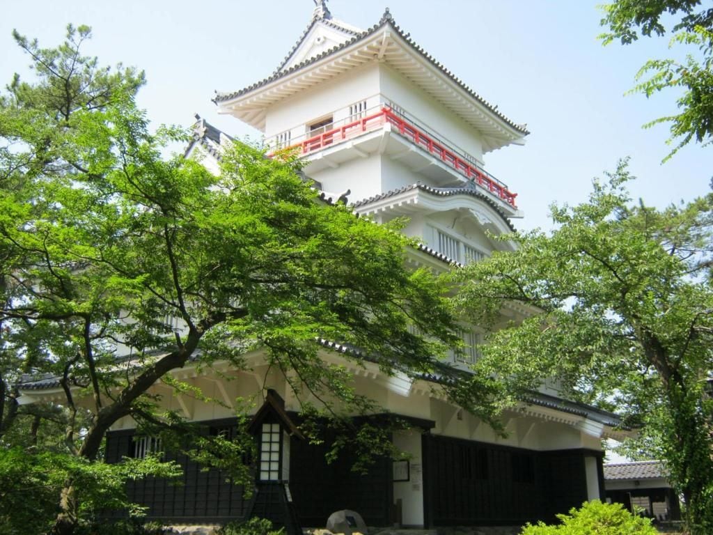 A traditional Japanese building with multiple tiers and a red railing on the upper level.