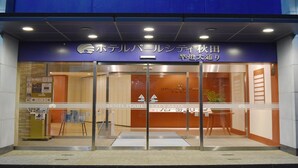 The entrance to Hotel Pearl City Akita with a glass door and a reception desk inside.
