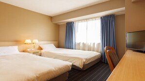 A hotel room with two beds, a desk, a TV, and a window with curtains.