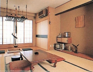 A traditional Japanese-style room with tatami flooring, a low table, and a hanging light fixture.