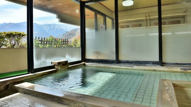 A traditional Japanese onsen with a view of mountains through large glass windows. - Hosonokan (Hakuba)