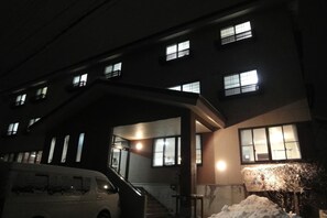 A multi-story building with illuminated windows and a staircase leading to the entrance.