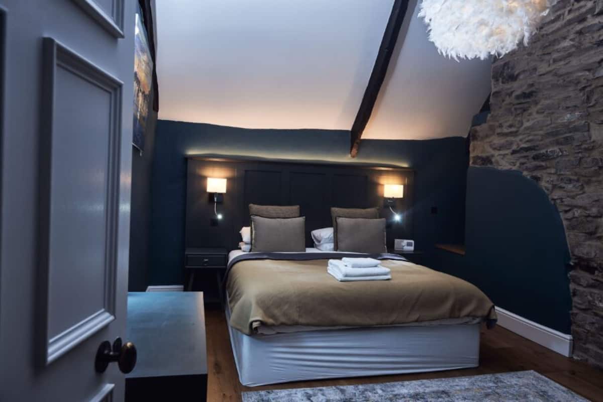 A bedroom with a bed, bedside tables, and a stone wall.