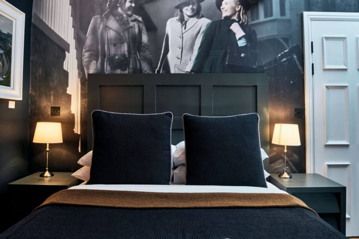 A hotel room with a large bed, two bedside tables with lamps, and a large wall mural.