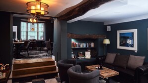 Um quarto acolhedor com lareira, estante de livros e área de jantar com mesa e cadeiras.