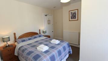 A bedroom with a bed, nightstands, a lamp, a framed picture, and a door.