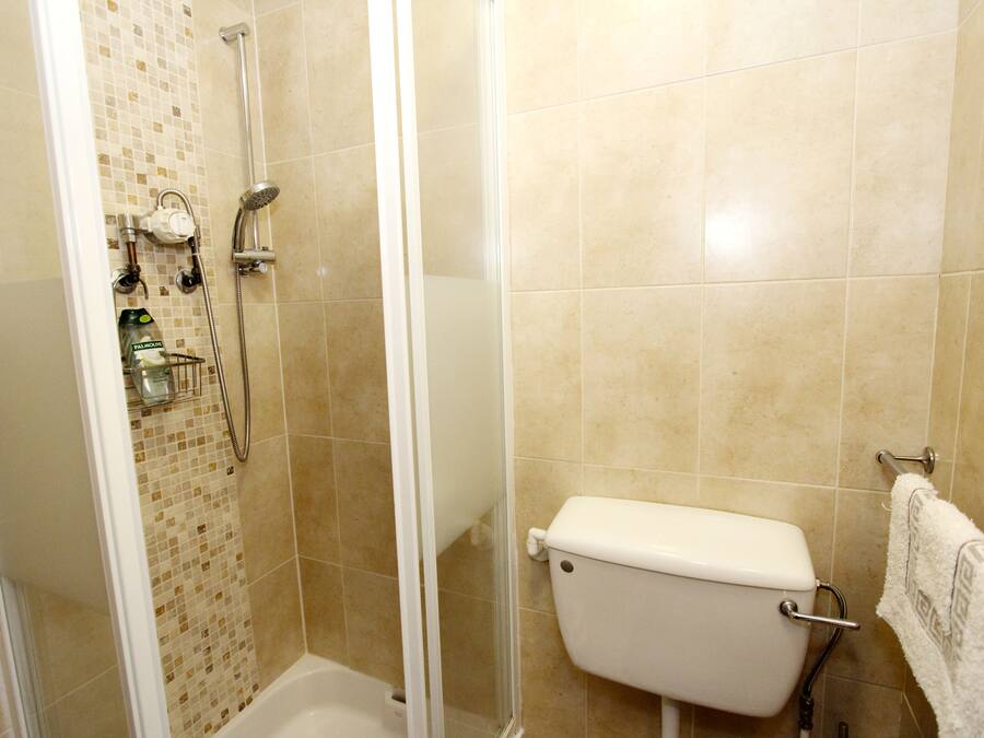 Ein Badezimmer mit Dusche, Toilette und gefliesten Wänden.