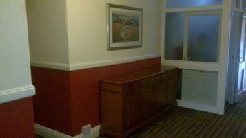 A hallway with a wooden bench, a framed picture on the wall, and a door with frosted glass panels.