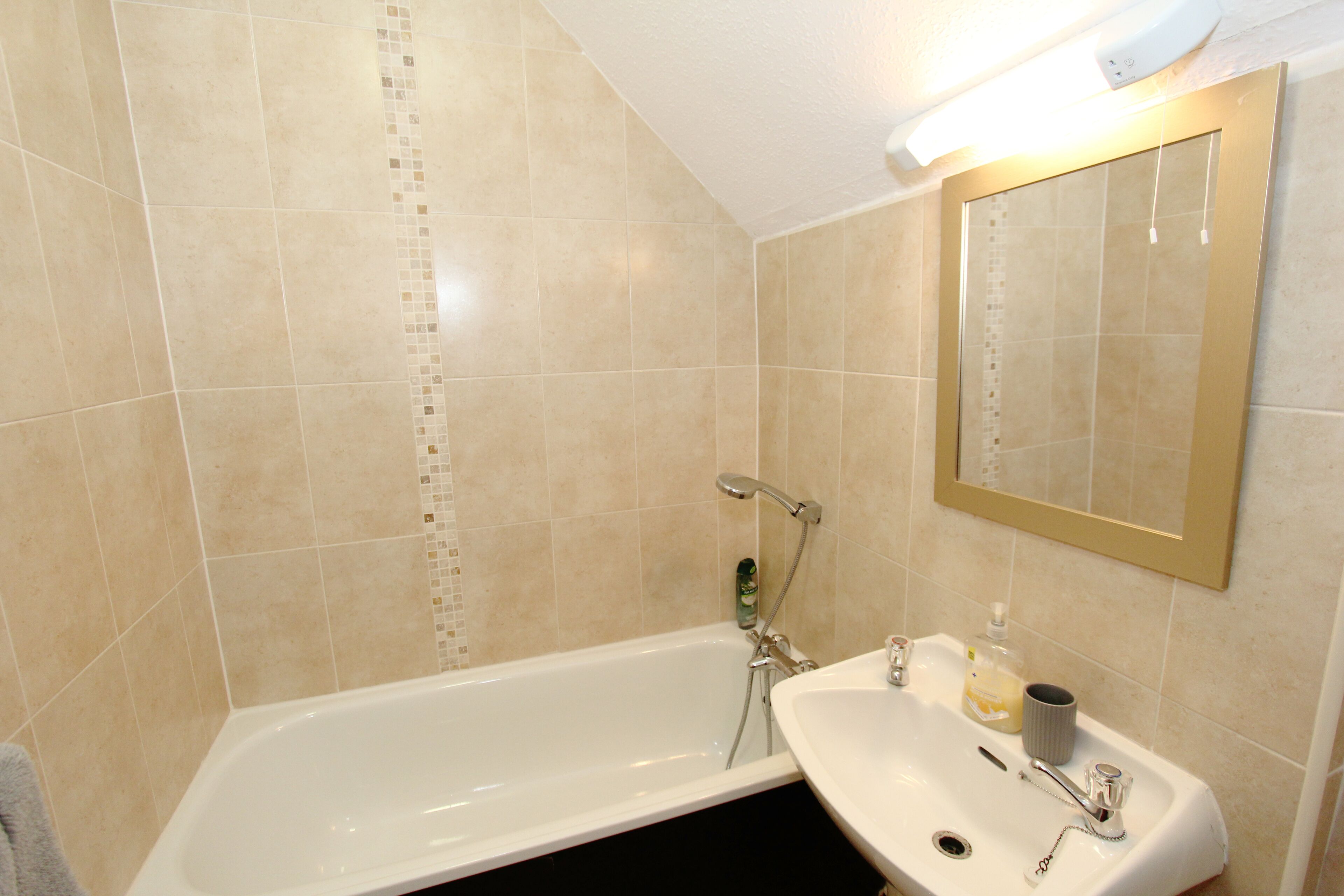 A bathroom with a bathtub, a sink, and a mirror.