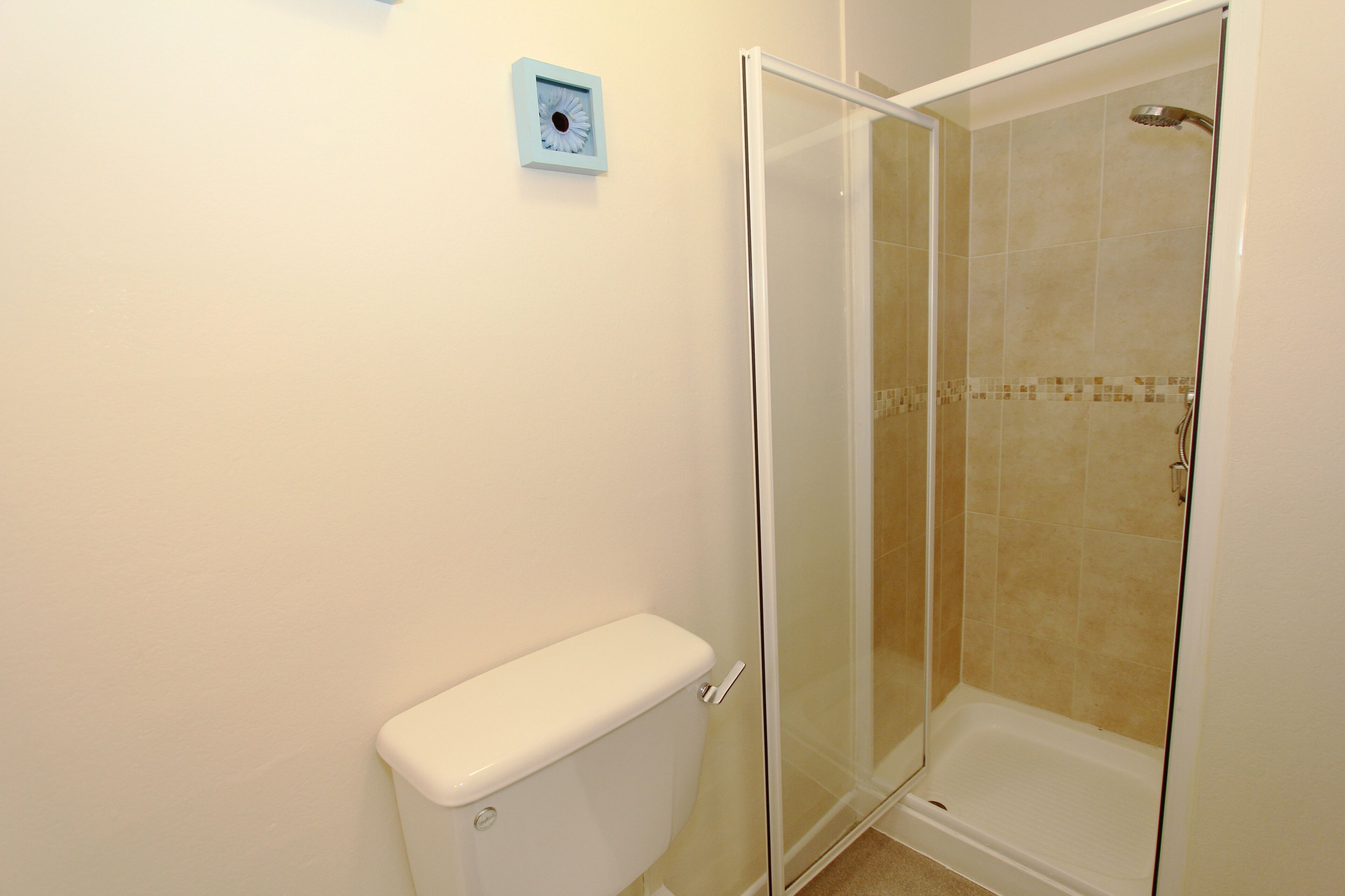 A bathroom with a glass-enclosed shower, a toilet, and a wall-mounted light fixture.