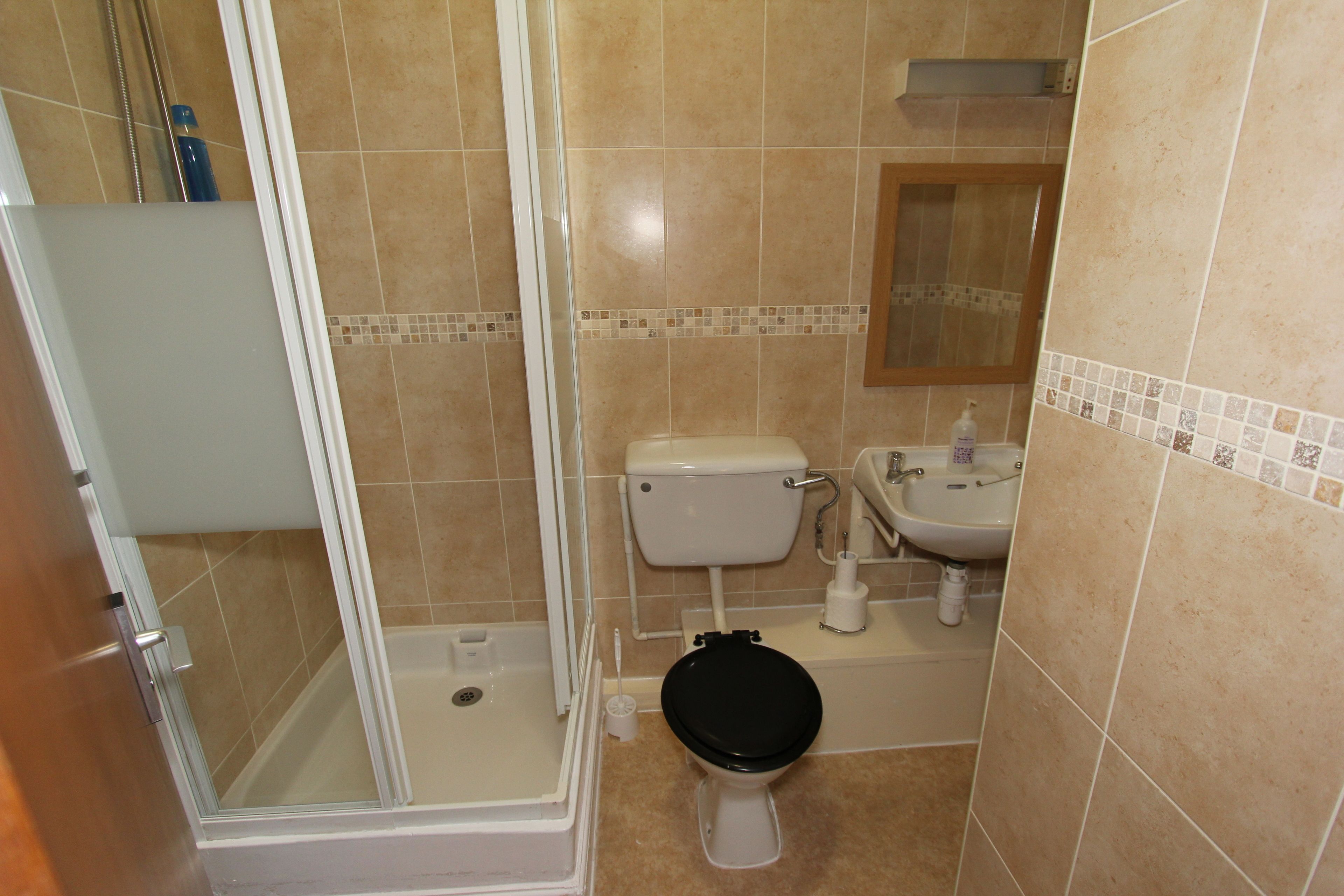 Ein Badezimmer mit Dusche, Toilette, Waschbecken und Spiegel.