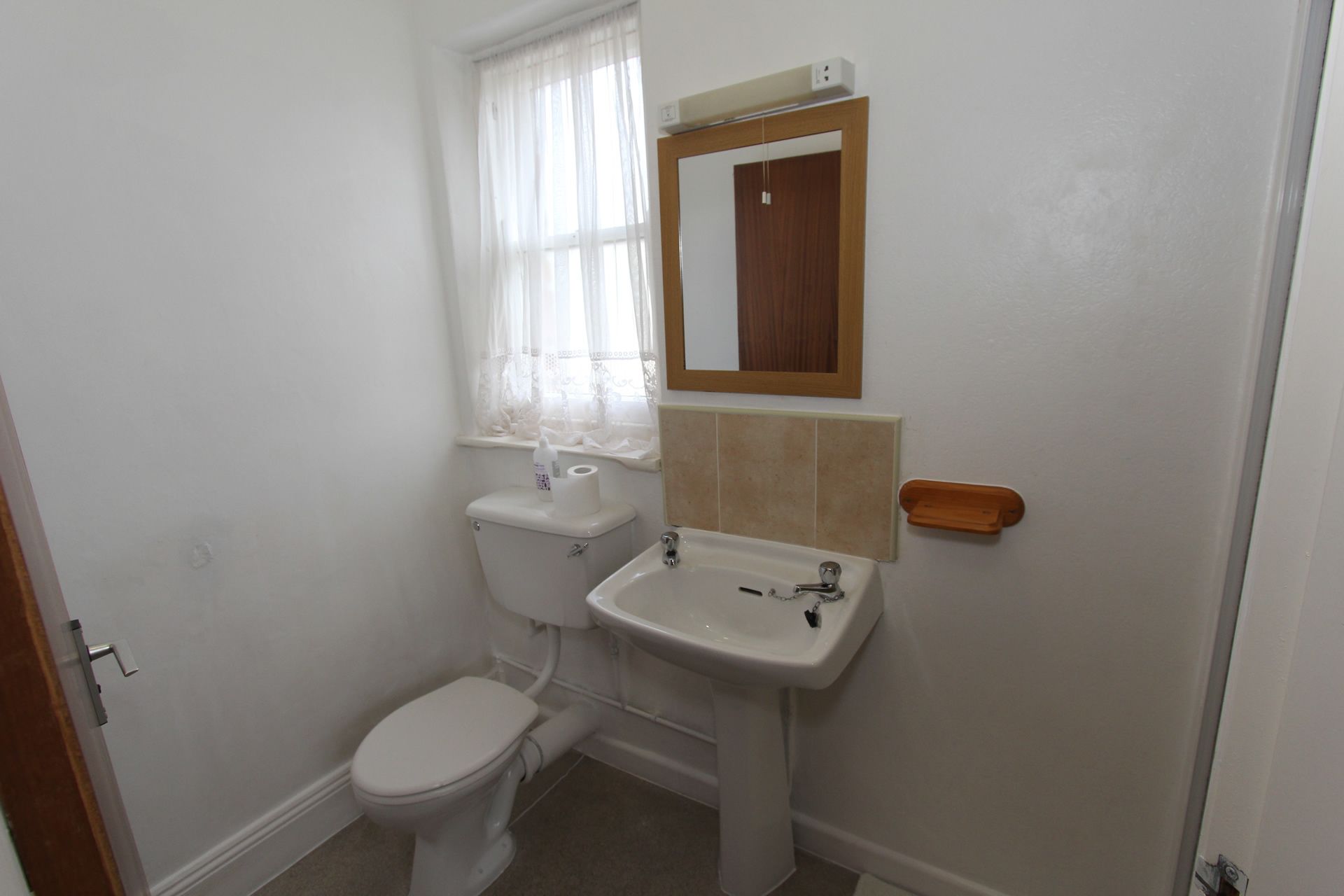 Un baño pequeño y limpio con inodoro, lavamanos y espejo.