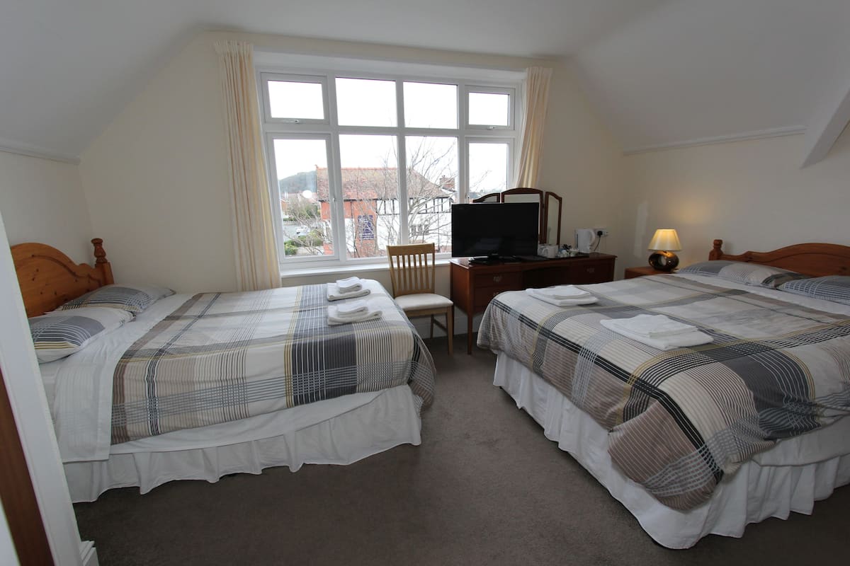 A bedroom with two beds, a desk, a chair, and a television.