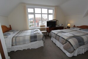 A bedroom with two beds, a desk, a chair, and a television.