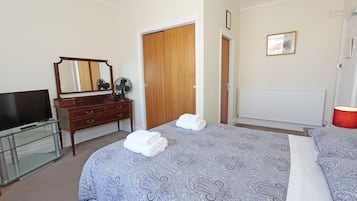 Een hotelkamer met een bed, een televisie, een dressoir en een spiegel.