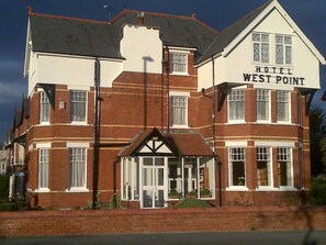 A two-story hotel named 'Hotel West Point' with a traditional architectural style, featuring a prominent entrance with a covered porch and multiple windows on each floor.