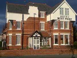 A two-story hotel named 'Hotel West Point' with a traditional architectural style, featuring a prominent entrance with a covered porch and multiple windows on each floor.