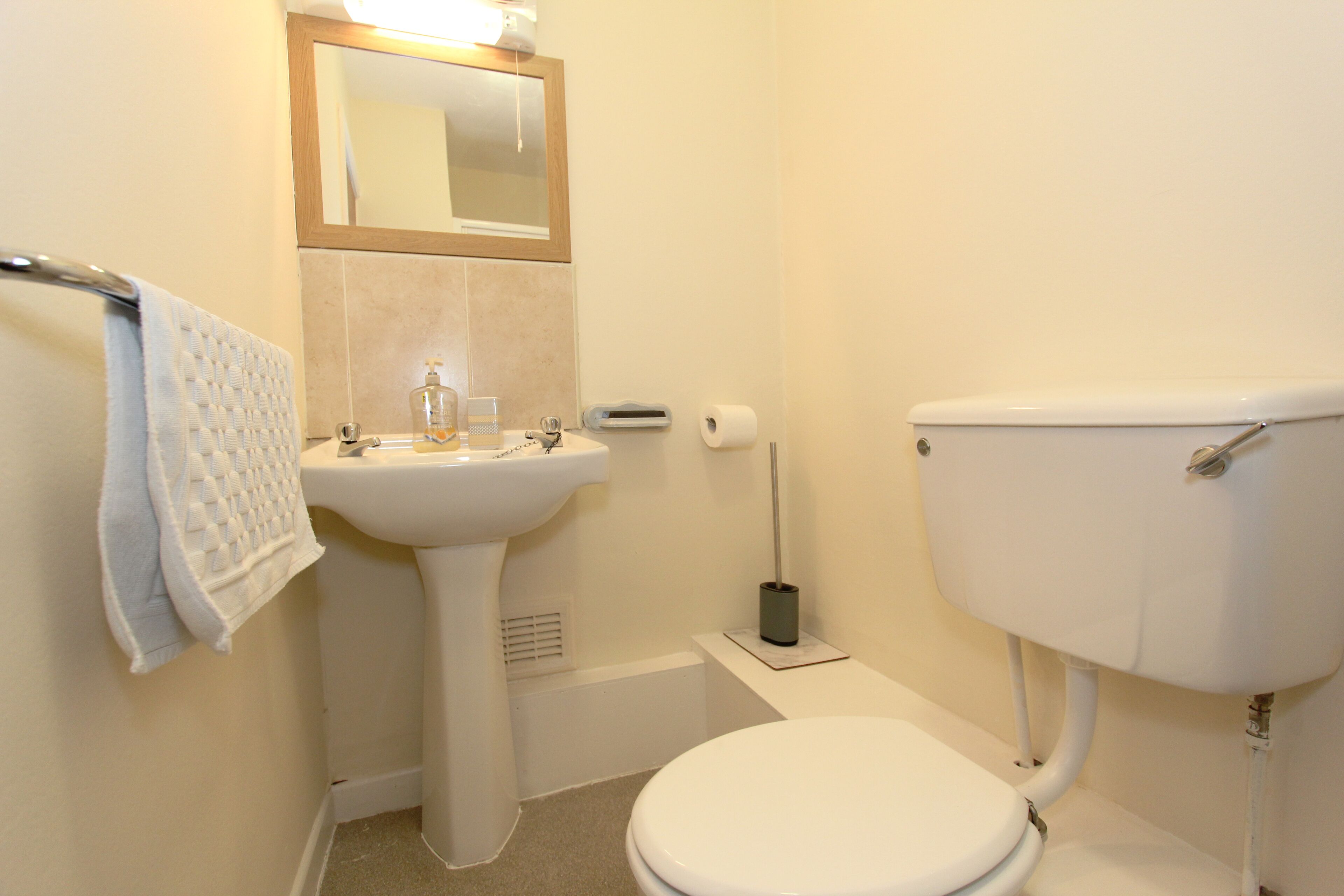 A bathroom with a toilet, sink, and mirror.